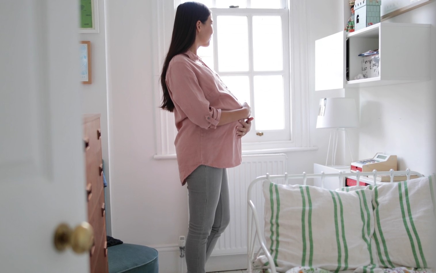 Pregnant woman standing in a bedroom 